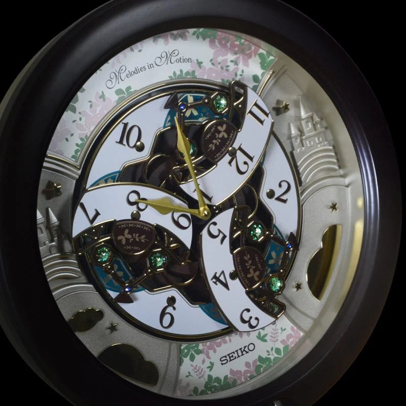 A close-up of a Seiko skeleton wall clock with a black round frame, white clock face segments, gold hands, and floral castle details on a black background.