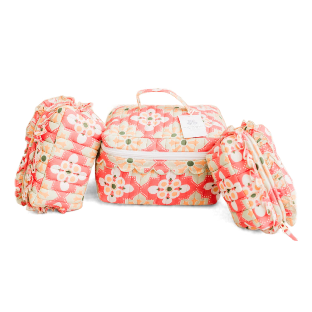 A quilted travel or diaper bag set with a coral pink, white, and yellow floral pattern, including a main zippered bag and two matching pouches, shown on a white background.