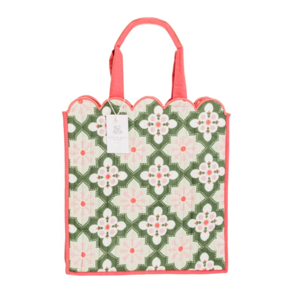A square reusable tote bag with a scalloped top edge, featuring a green, white, and pink floral pattern with coral pink handles and trim, shown on a plain white background.