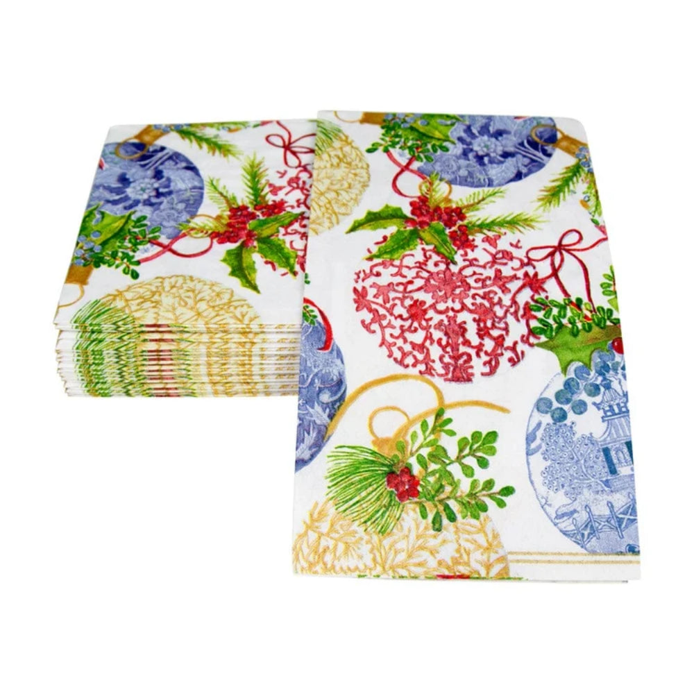 A stack of white guest towels featuring a festive Christmas print with red ornaments, green holly leaves, pinecones, blue and gold plates, and red bows, shown on a plain white background.