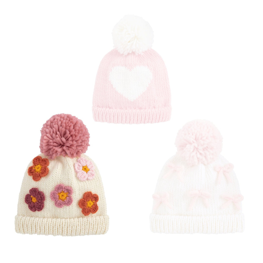 Flower knitted hat with floral patterns and pink pom-pom on a white background.