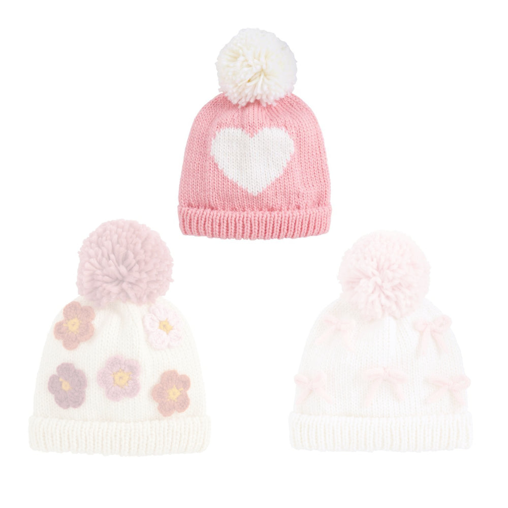 Heart pink knitted hat with a heart pattern and a white pom-pom on a white background.