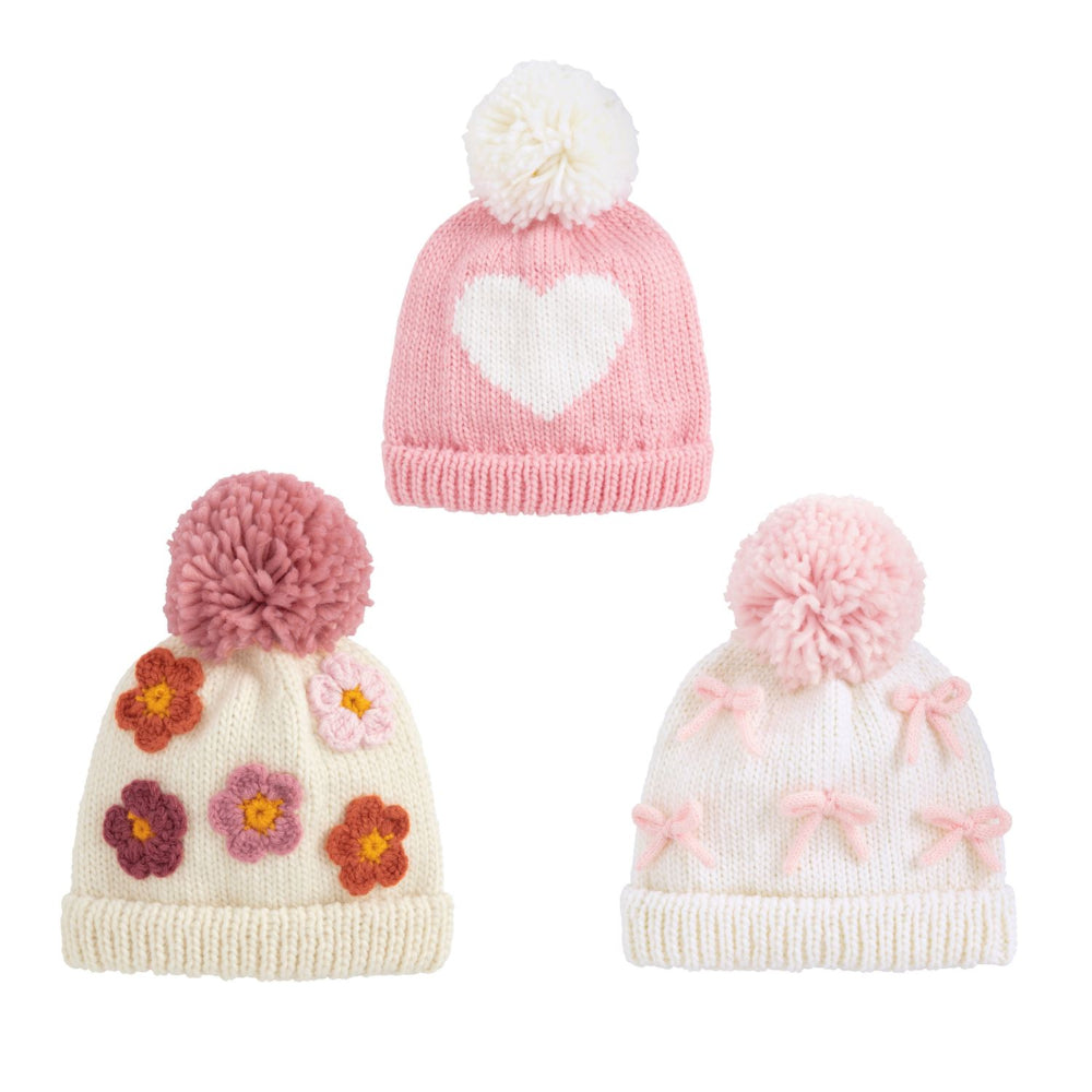 Three knitted hats with pom-poms on a white background.