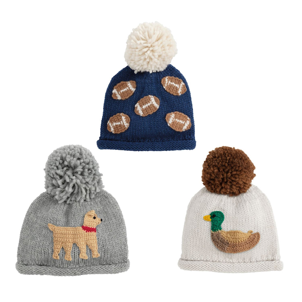 Three navy, grey and white knit hats with pom-poms and embroidered designs on a white background.