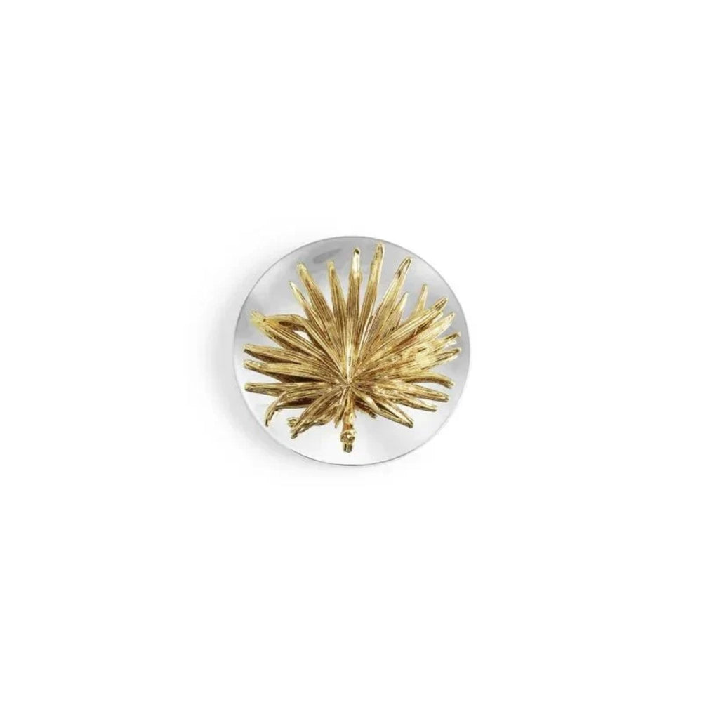 A round silver-toned brooch featuring a textured, starburst-like gold center, displayed on a clean white background.