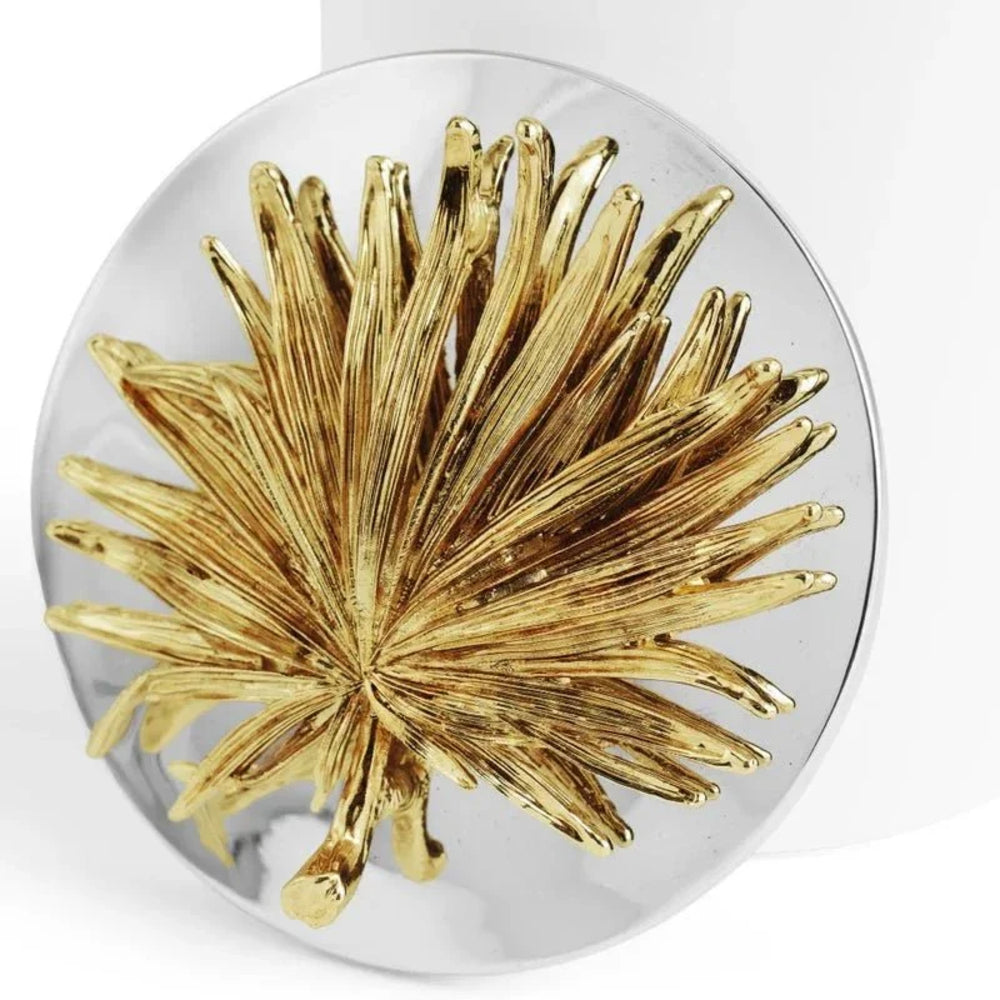 Gold leaf design on a round silver pendant against a white background