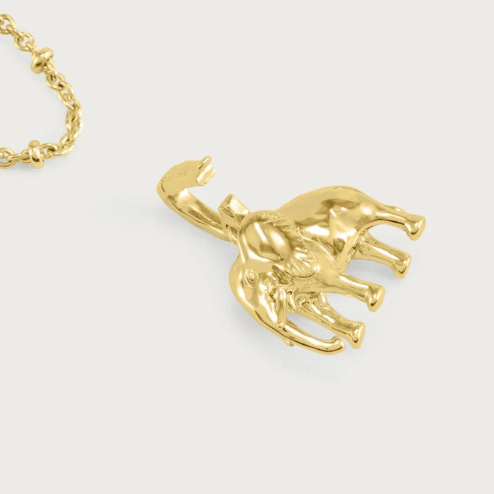 A gold-toned elephant pendant necklace on a matching chain, displayed against a light gray background.