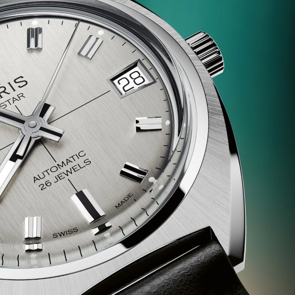 Close-up of a luxury watch with detailed face and brand name on a teal background