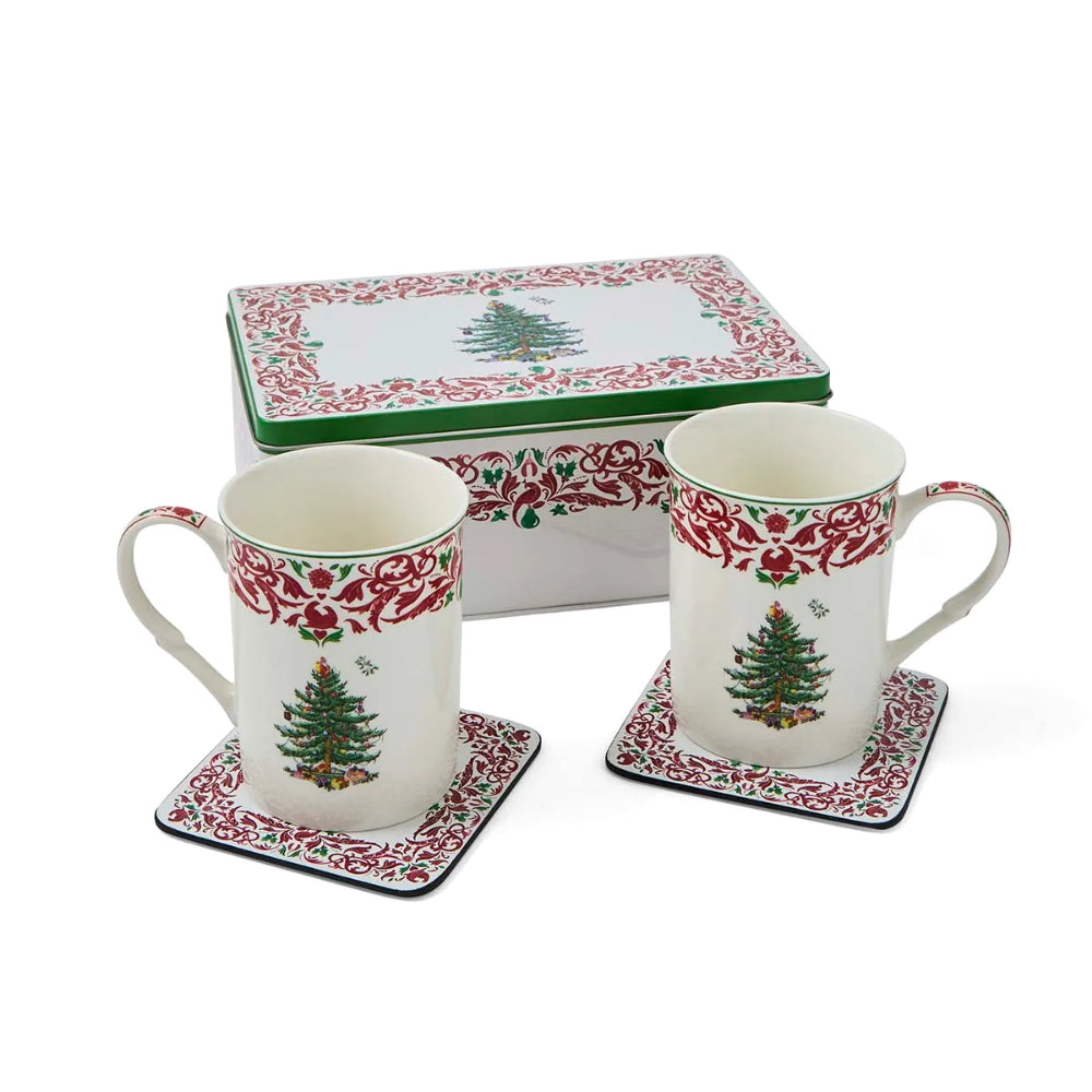 A Christmas-themed ceramic mug and coaster set with a matching storage box. The white ceramic mugs feature a red floral border and a green Christmas tree with small ornaments, and are shown on matching square coasters with the box behind them on a white background.