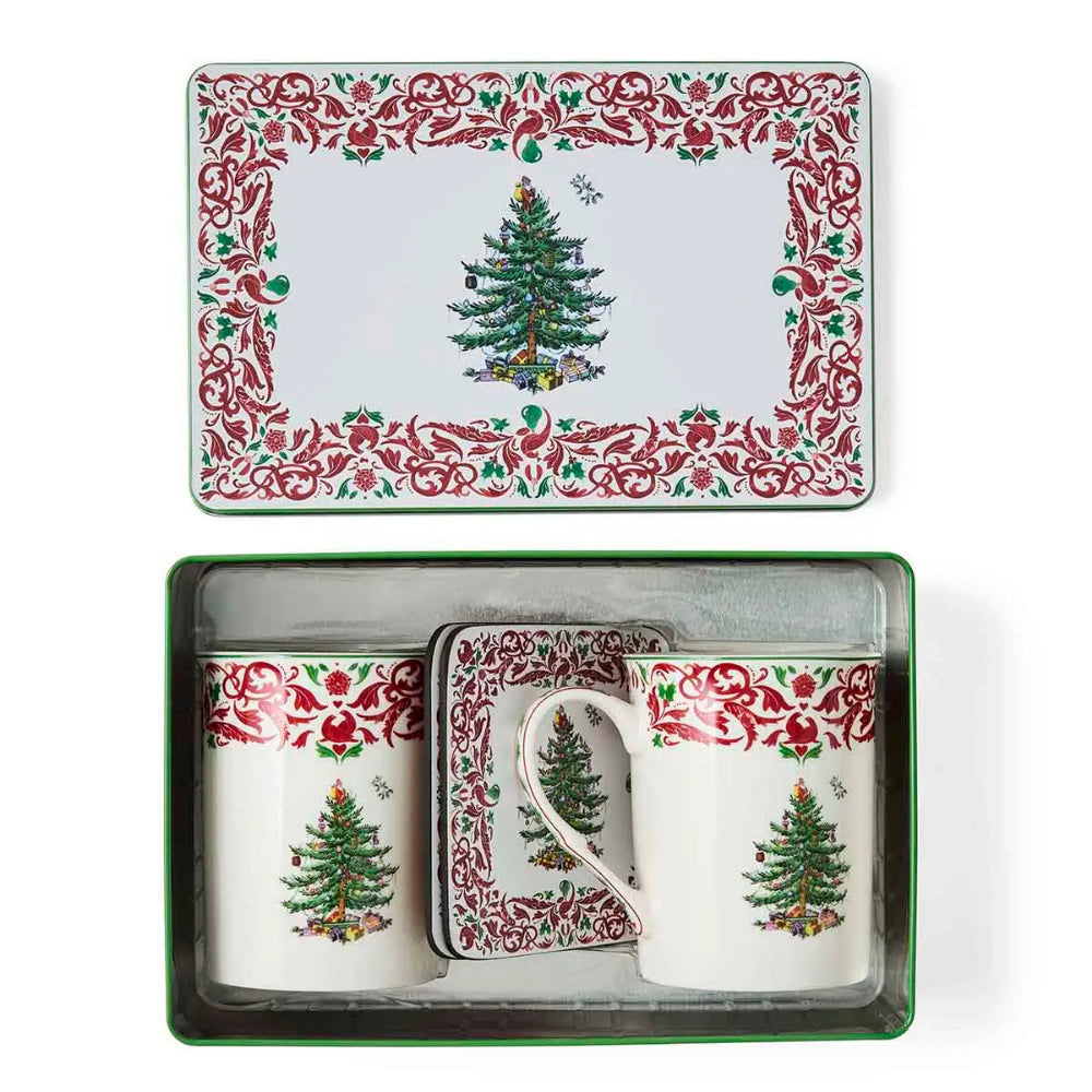 A Christmas-themed ceramic mug and coaster set in a green gift box, shown alongside its matching decorative tin lid on a white background.