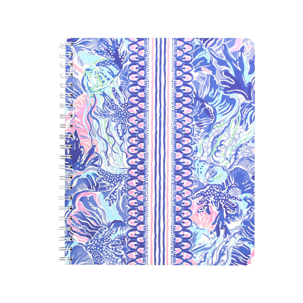 A spiral-bound notebook featuring a vibrant blue, pink, and white tropical floral pattern on a clean white background.