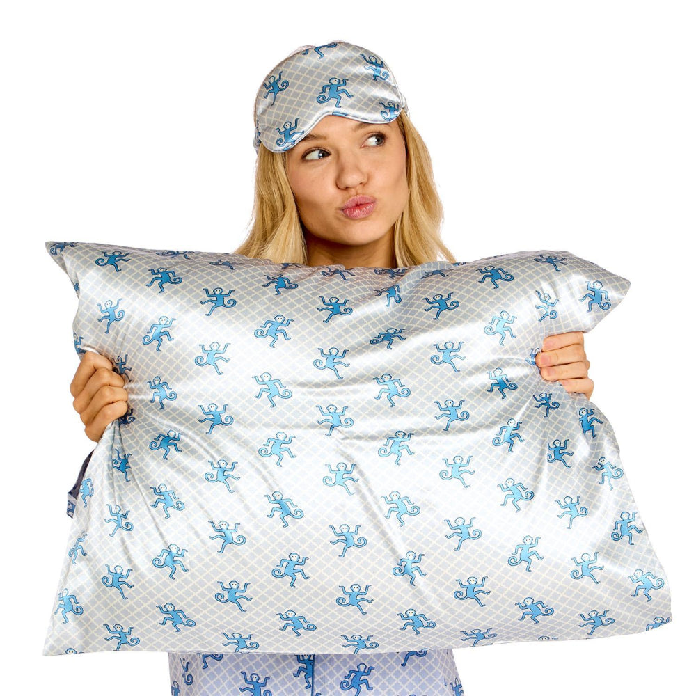 A woman wearing matching pajamas holds up a large pillow and a matching sleep cap against a plain white background. The bedding set features a light gray and white patterned fabric with a repeating blue octopus motif.