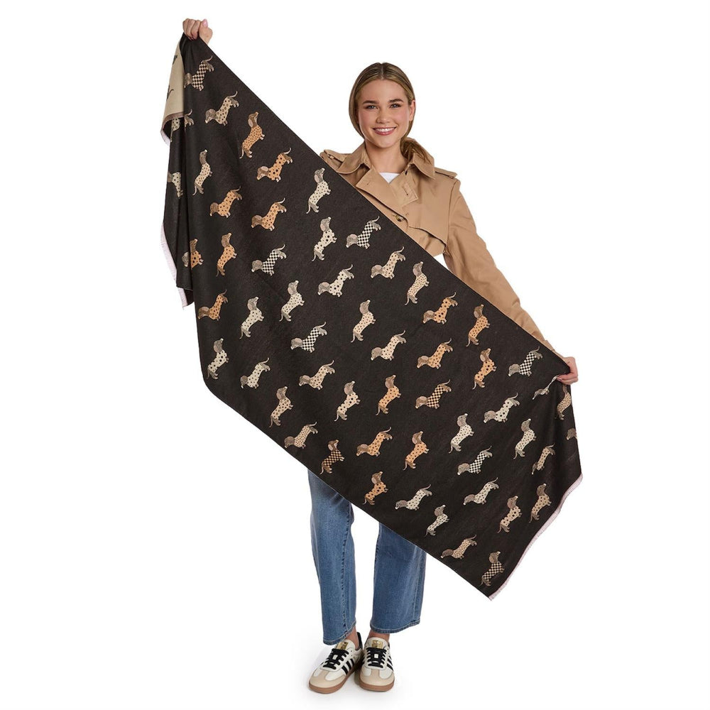 Person holding a reversible black & beige scarf with   differant shades of a beige dachshund dog patterns in on a white background.
