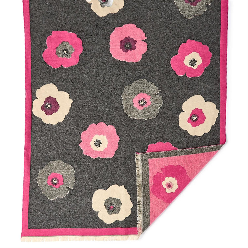 Close up of a floral patterned fabric with pink, gray, and beige flowers on a dark background against a white backround.