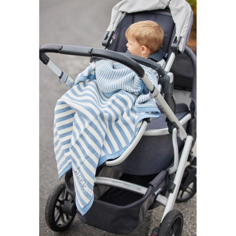 Child in a stroller with a blue and white striped blanket