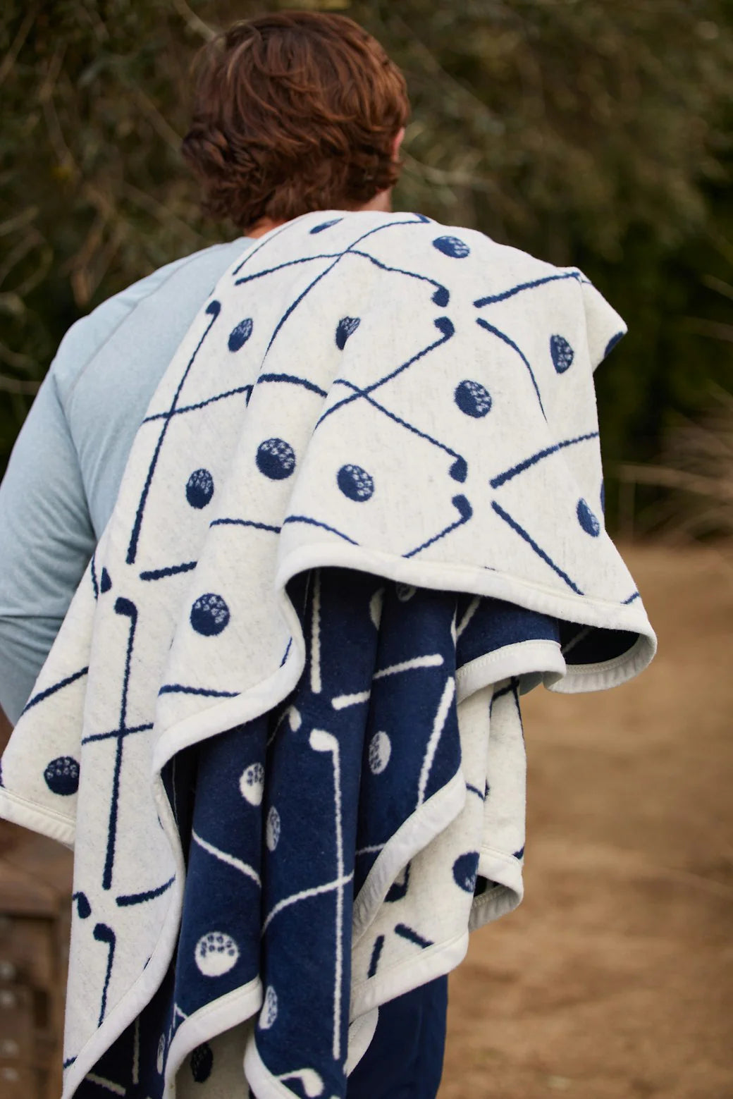 Person holding a blue and white patterned golf blanket outdoors