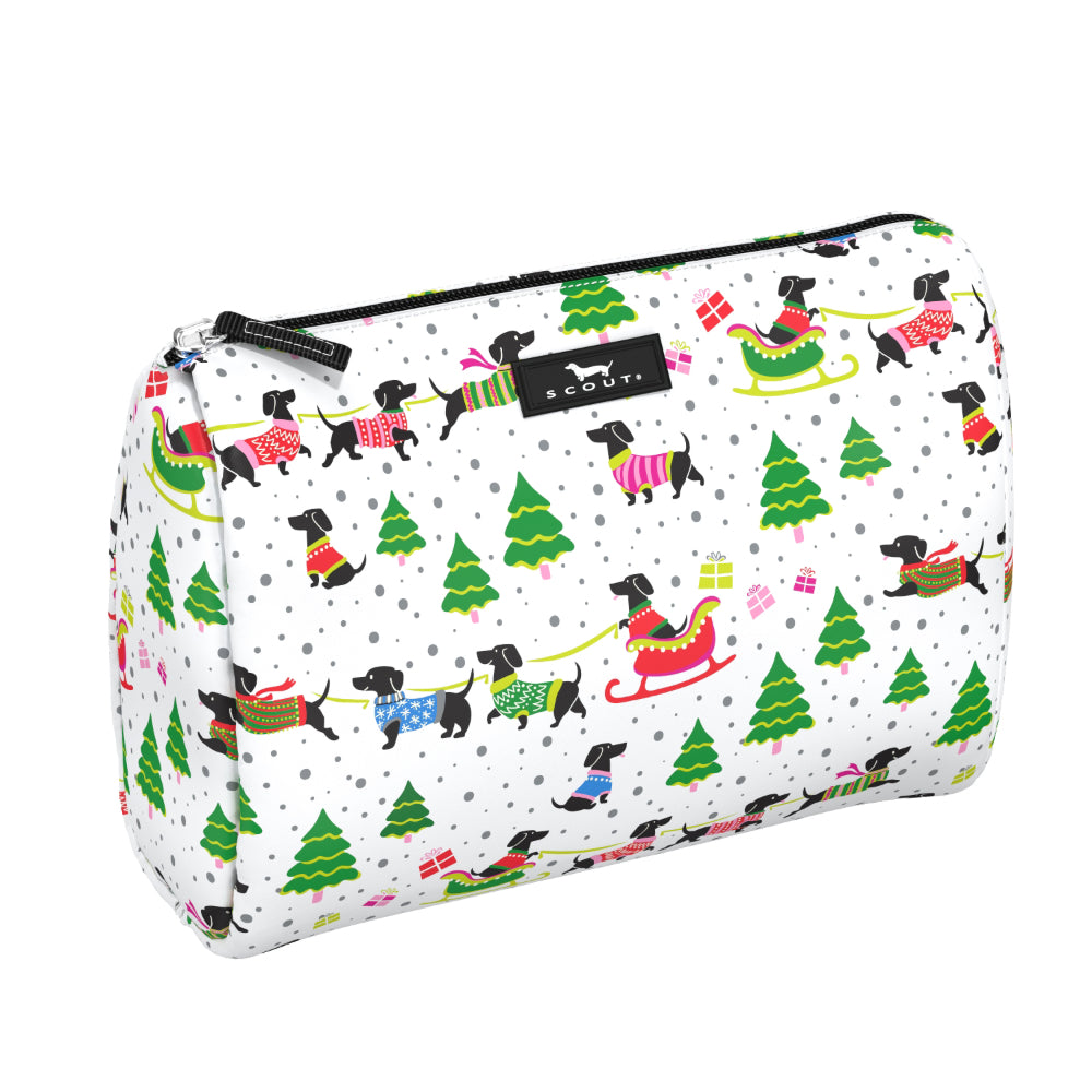 A white cosmetic pouch with a festive Christmas print featuring black dachshunds, green Christmas trees, and colorful holiday accessories. The pouch has a black zipper with a black brand label that reads 'scout'.