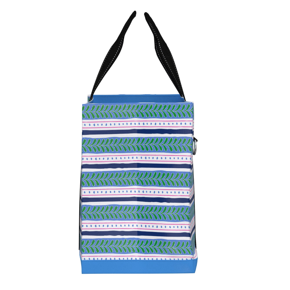 A tote bag with a blue base, decorated with horizontal stripes of green leaf patterns and white dotted lines, featuring black shoulder straps.