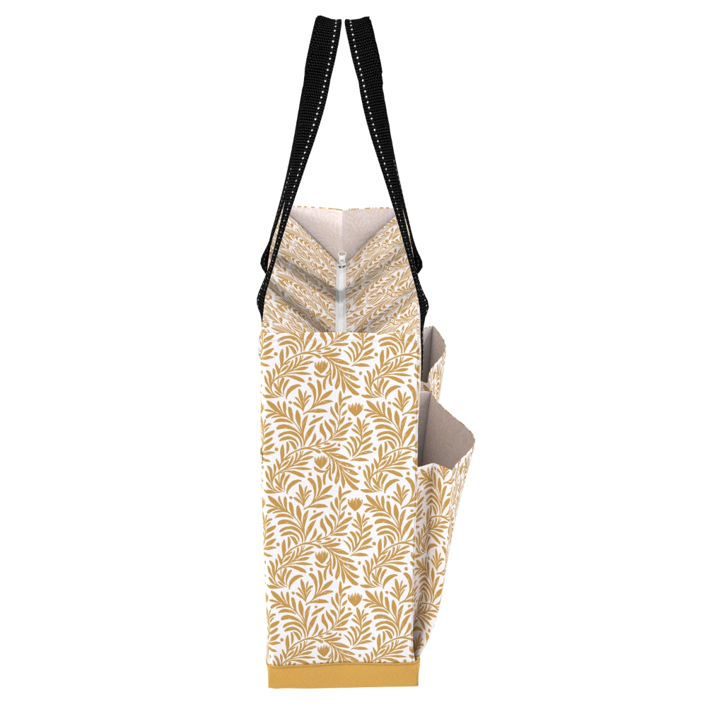 A tote bag with a white and gold botanical leaf pattern, featuring black shoulder straps with white stitching and a gold zipper at the top.