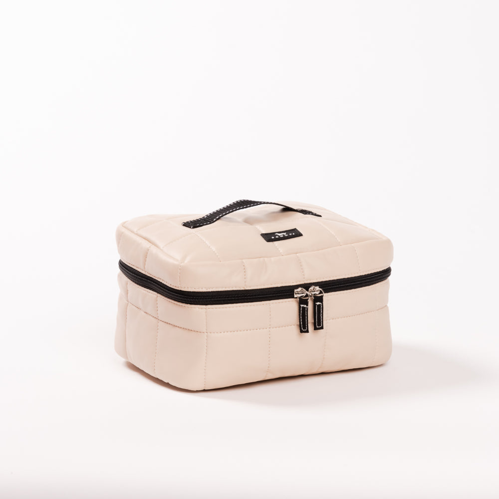 Beige quilted cosmetic bag with black zippers on a white background