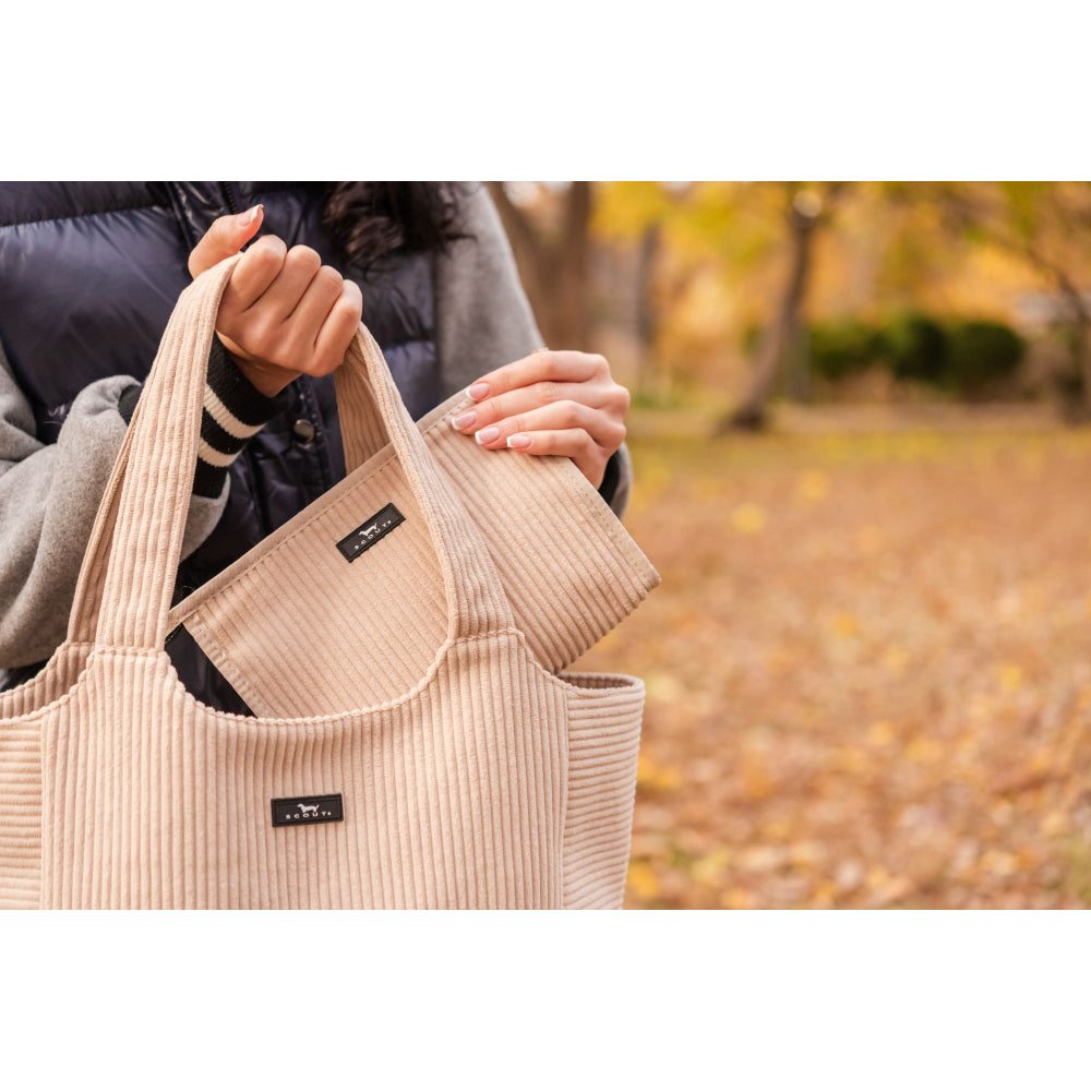 Beige tote bag held by a person with a blurred autumn background