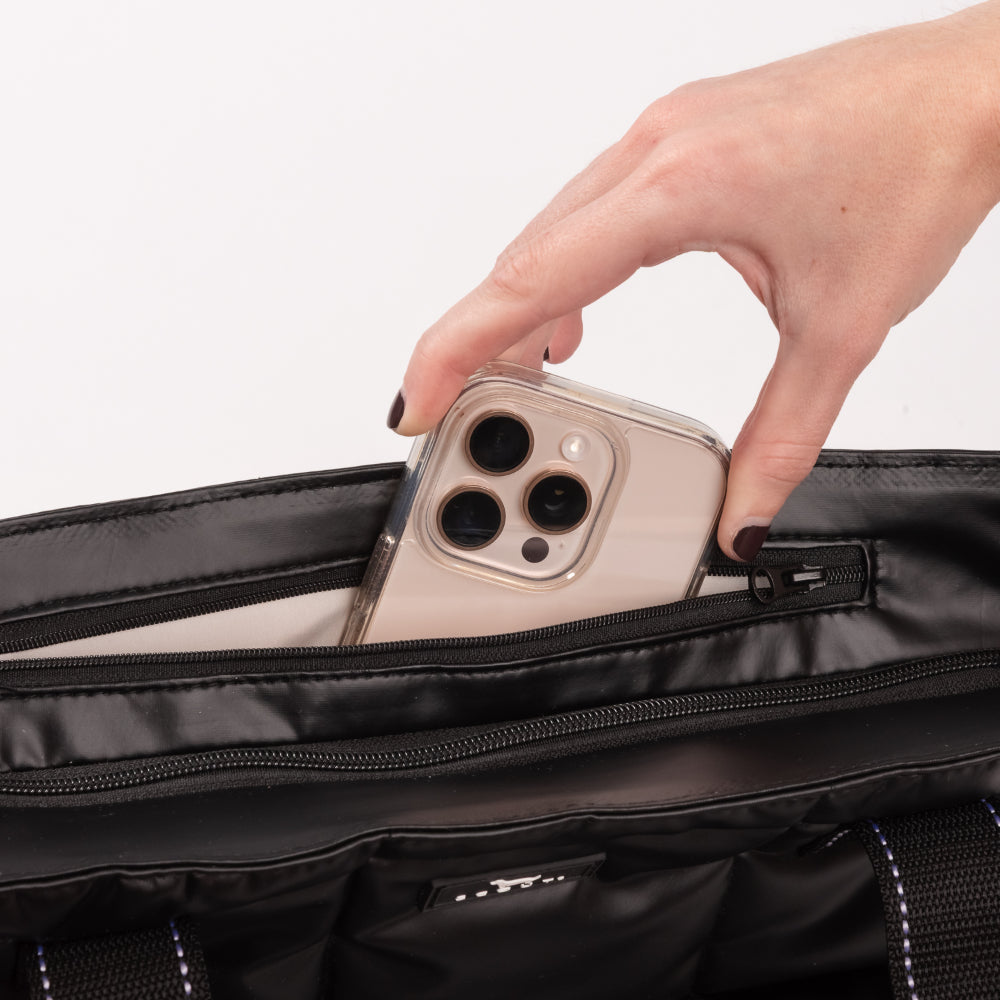 Person placing a phone into a black bag with a white background