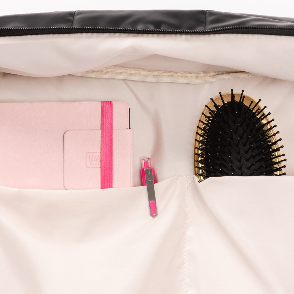 Close-up of a beige travel bag with a pink notebook and black hairbrush inside.