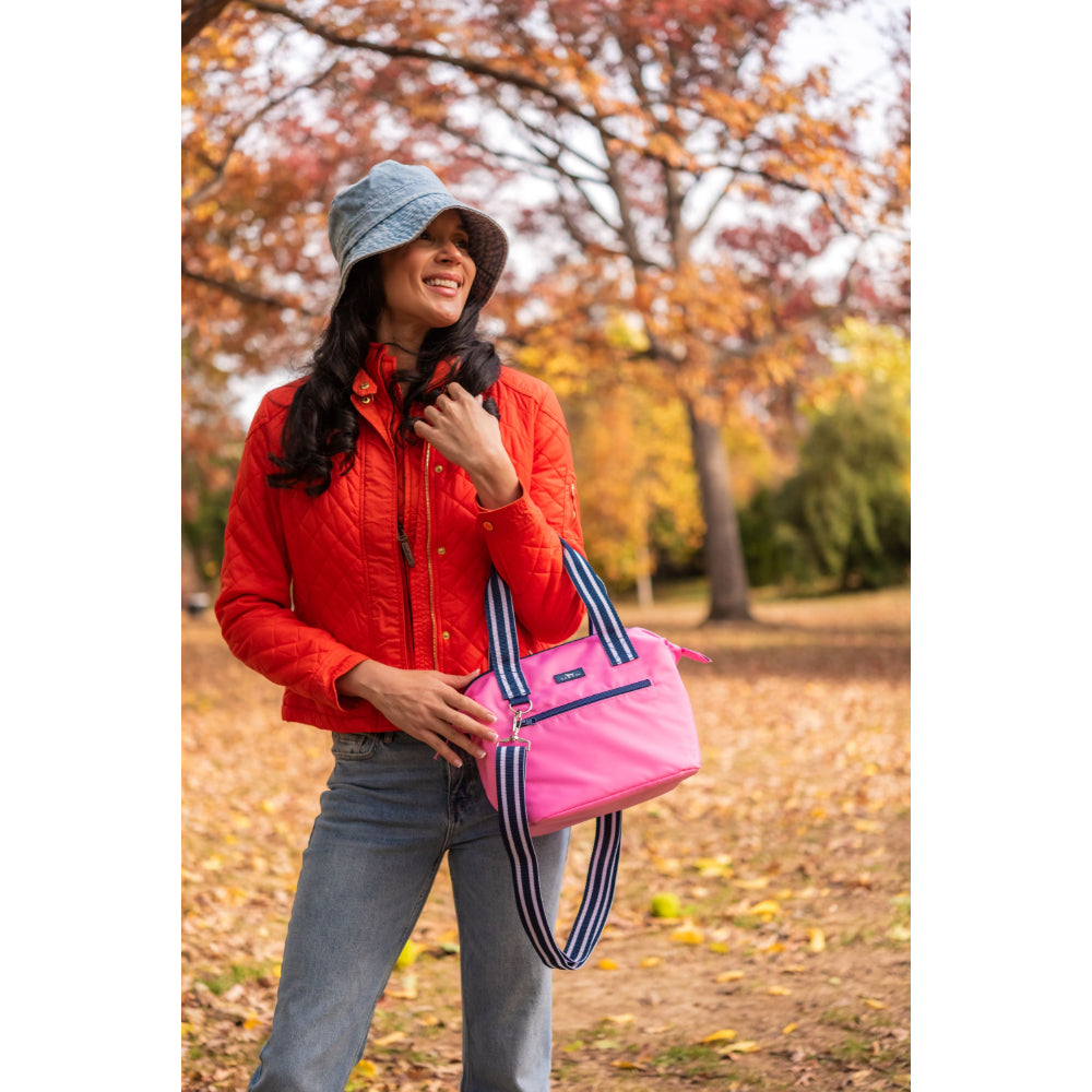 Woman in a red jacket holding a pink cooler bag in an autumn park