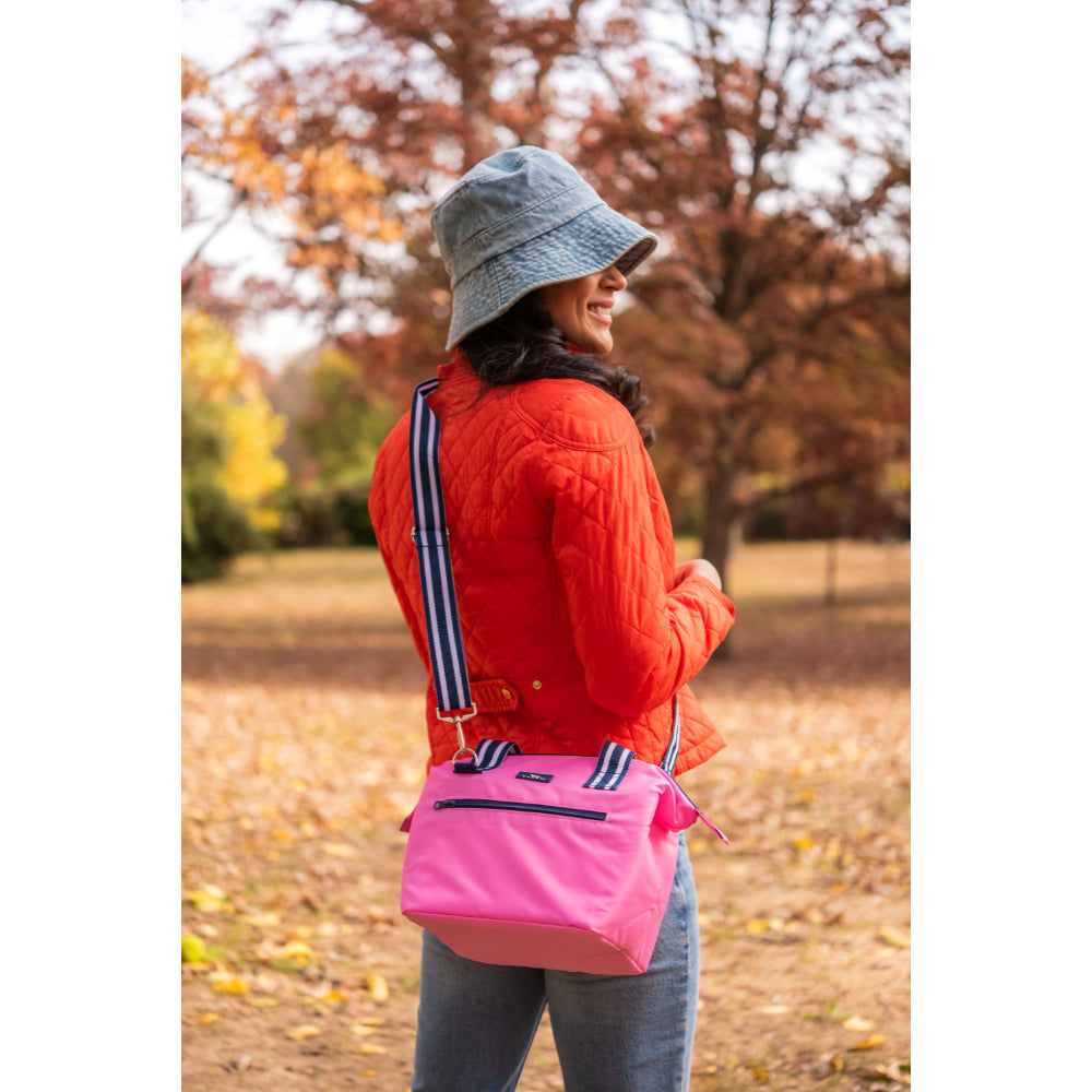 Person wearing a red jacket and gray bucket hat with a pink cooler bag in an autumn park.