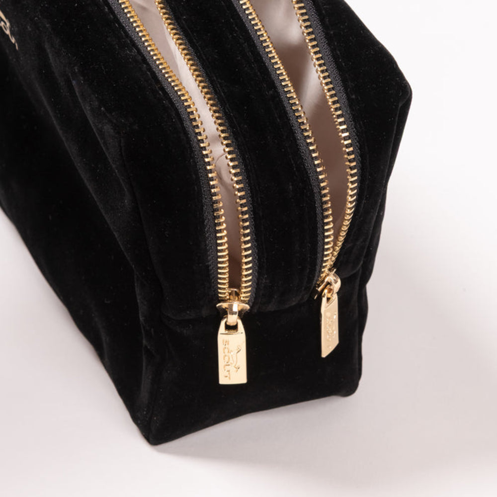 Black velvet pouch with gold zipper and tags on a white background