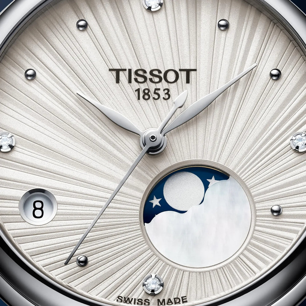 Close-up of a Tissot 1853 watch dial with a sunburst silver and white mother-of-pearl face, a moonphase window at the 6 o'clock position, and silver hour markers.