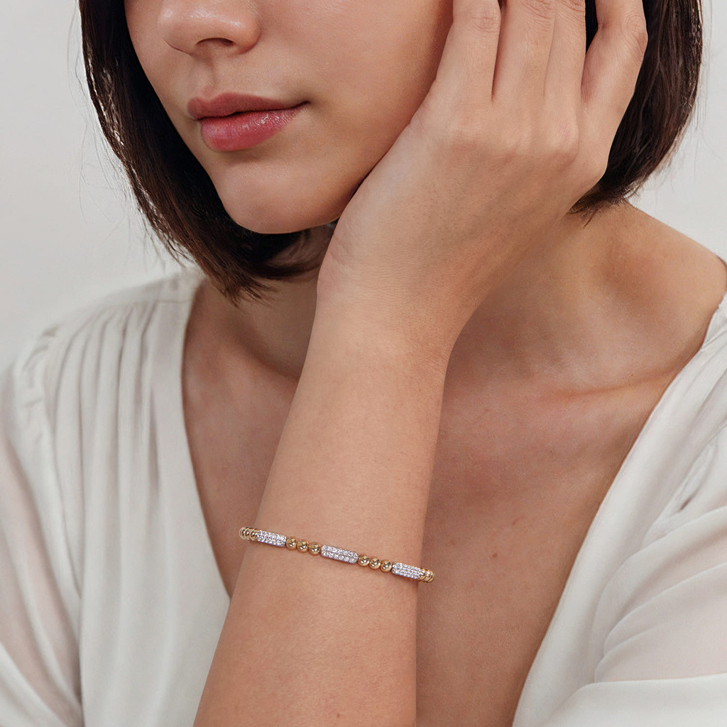 model wearing gold beaded bangle with clear stones on natural background