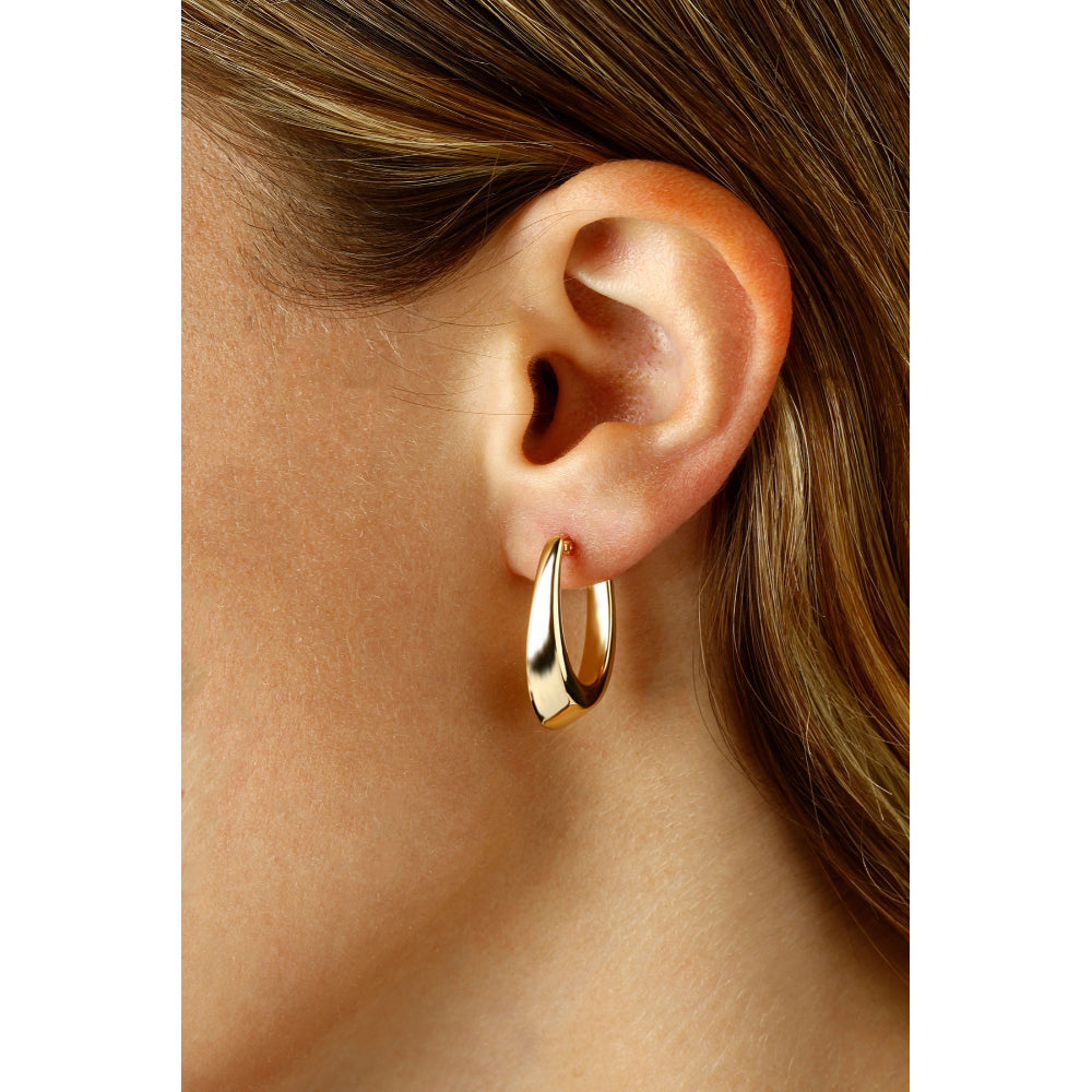 Gold hoop earring worn by a person with blonde hair.