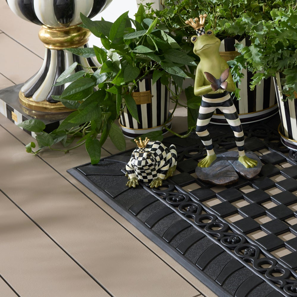 Decorative frog figurines on a checkered mat with plants in the background