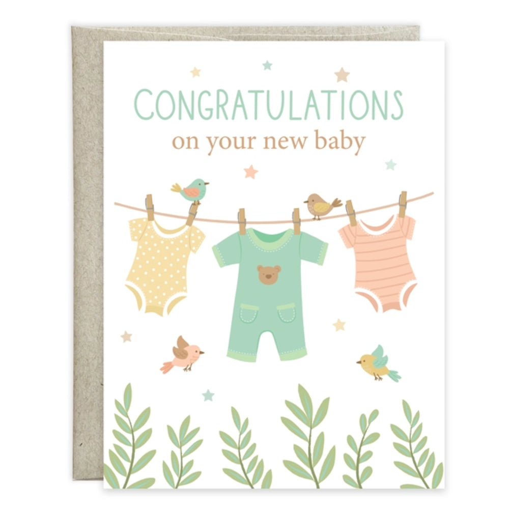 A baby congratulations card with a kraft envelope, featuring the text 'CONGRATULATIONS on your new baby' above an illustration of three baby onesies hanging on a clothesline with small birds and green leaves at the bottom.