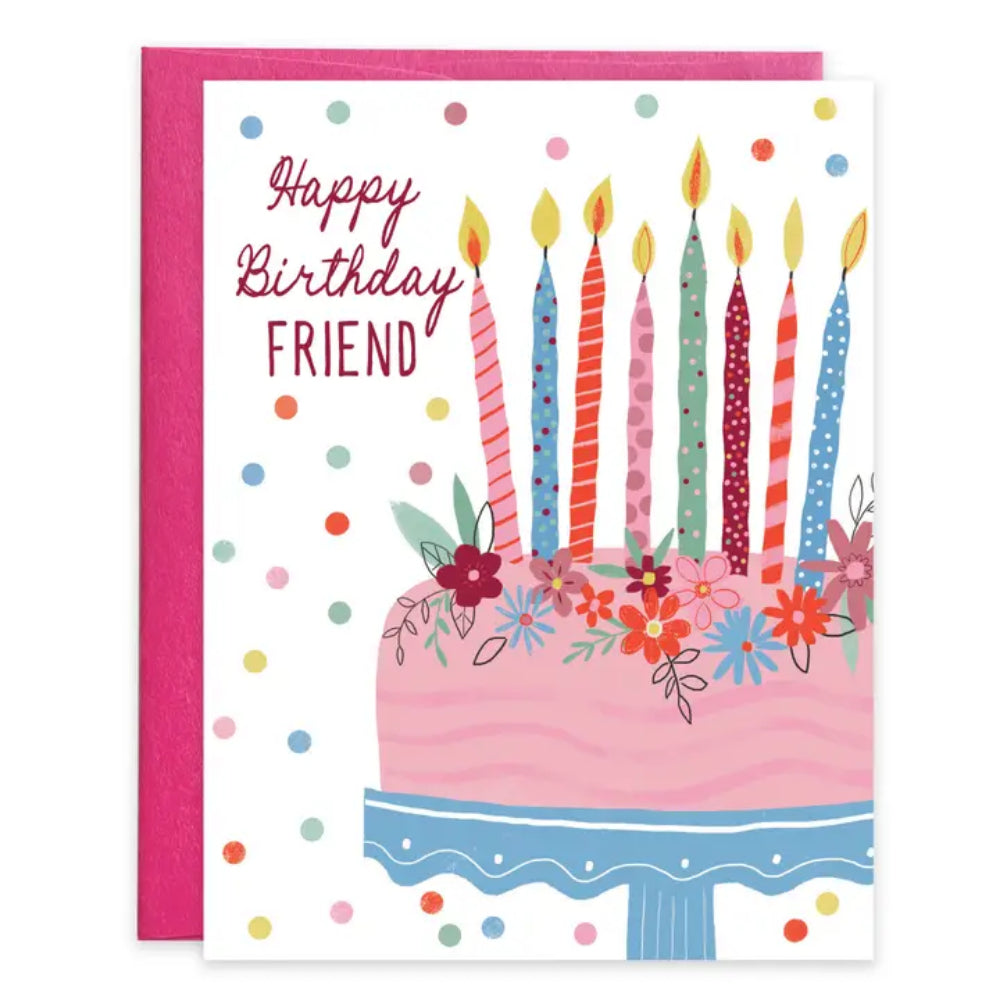 A birthday greeting card with a pink envelope behind it. The card reads 'Happy Birthday FRIEND' above an illustrated pink birthday cake with colorful candles, flowers, and confetti dots on a white background.