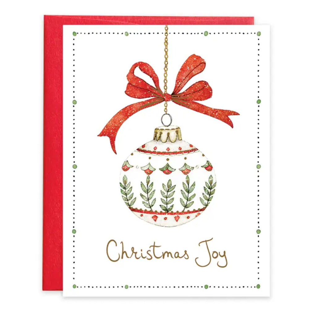 A Christmas greeting card with an ornament and christmas joy on the card on a white background. 