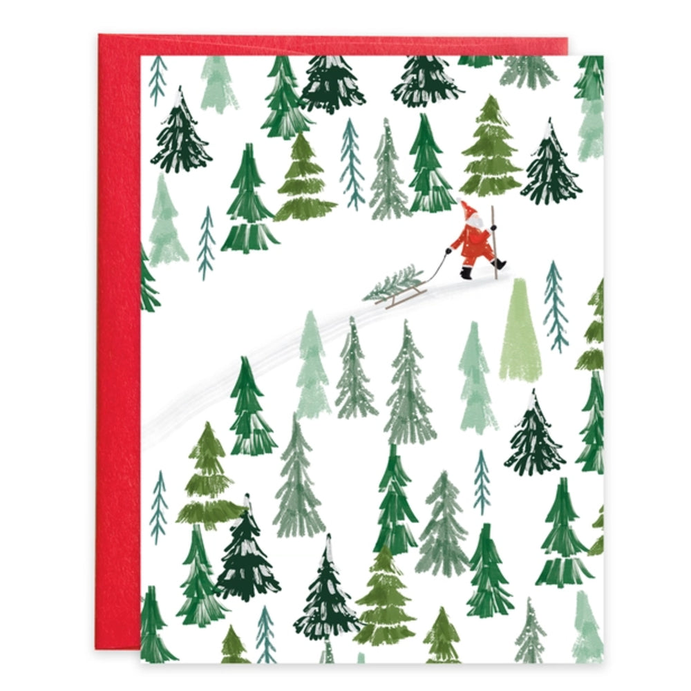 A square greeting card with a red envelope, featuring a white background printed with a pattern of green and light green pine trees and a small red figure skiing across the scene.