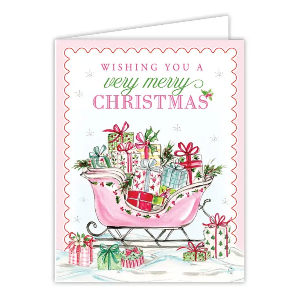 A Christmas greeting card with a pink border and the text 'Wishing you a very merry Christmas' above an illustration of a pink sleigh filled with wrapped presents.