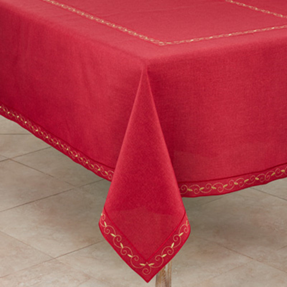 A red tablecloth with gold embroidered borders draped over a table, with a tiled floor visible underneath.