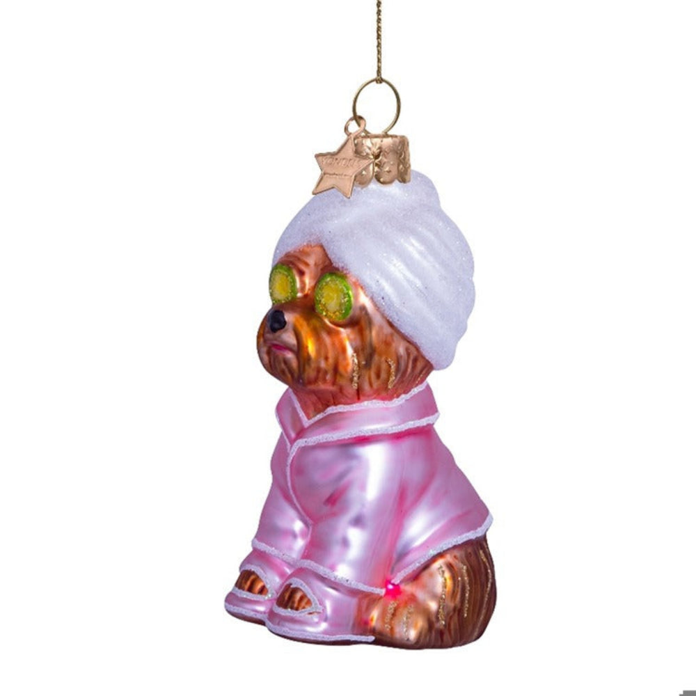 Glass ornament of a dog wearing a pink outfit and white turban on a white background