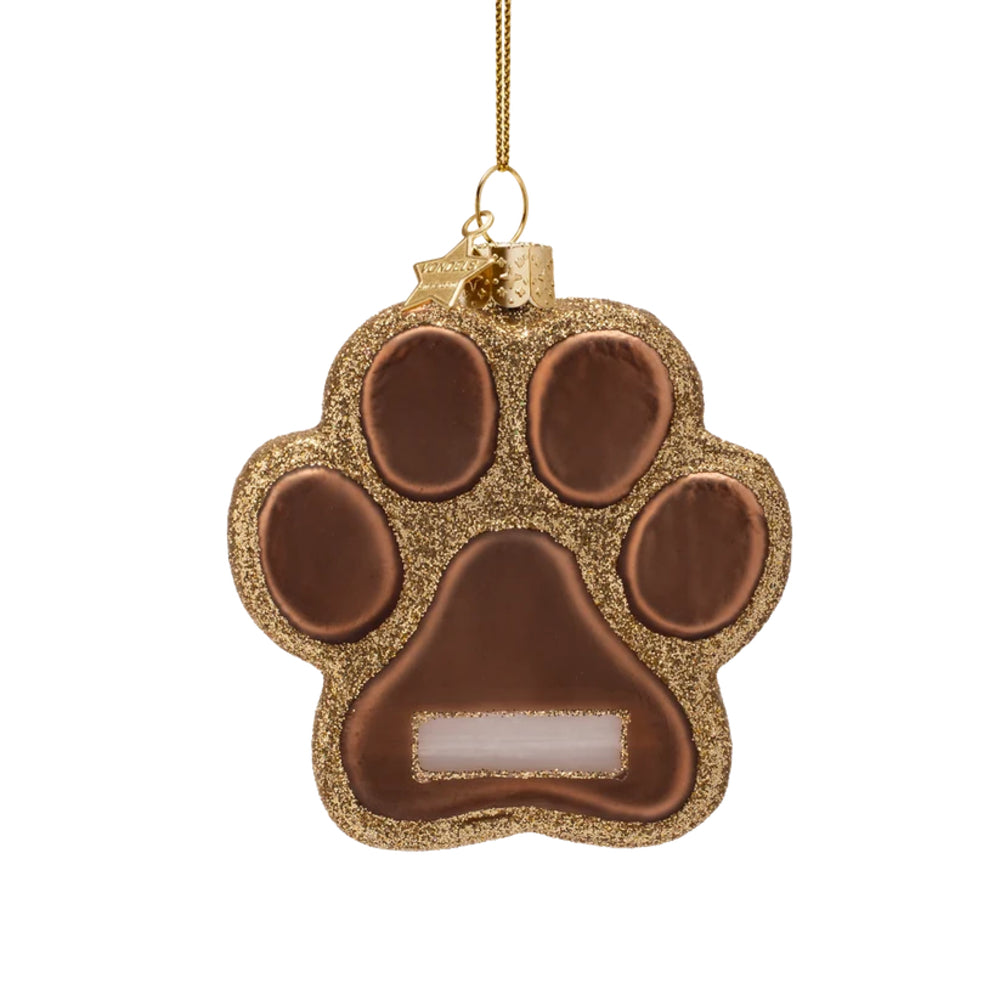 A gold and bronze paw print Christmas ornament with a glittery gold border, hanging from a gold string on a white background.