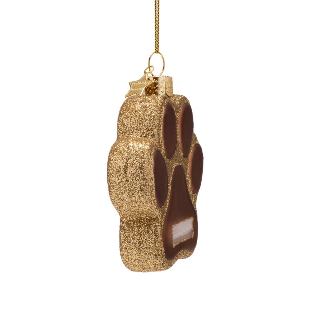 A gold glitter paw-print shaped Christmas ornament with dark brown paw pad details and a gold hanging loop, shown against a plain white background.