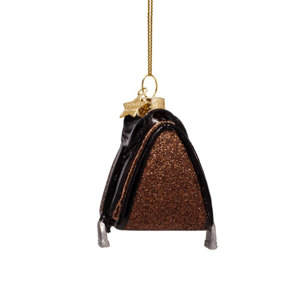 Decorative ornament shaped like a black and gold saddle on a white background