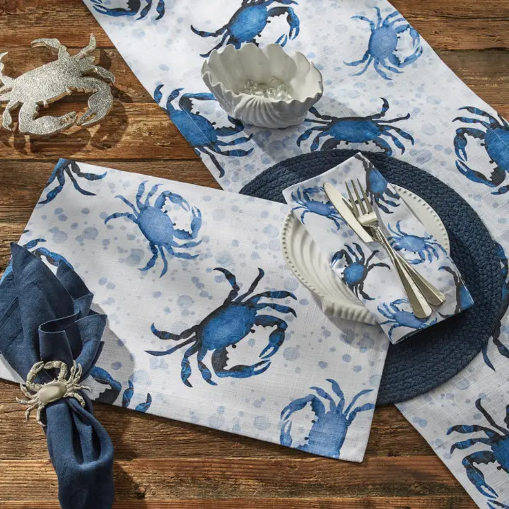 Blue crab napkins and table runners on wooden surface with other crab display items. 