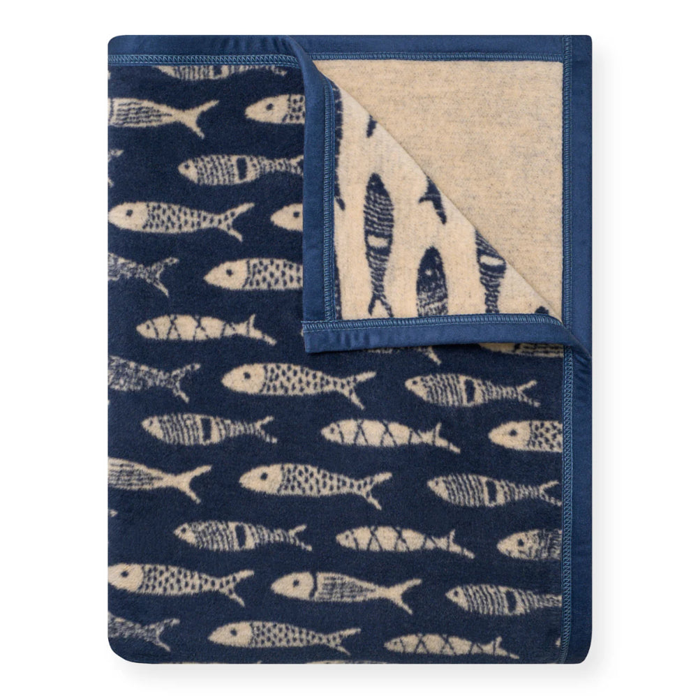 Folded blanket with fish pattern on one side and sailboat pattern on the other, on a white background.