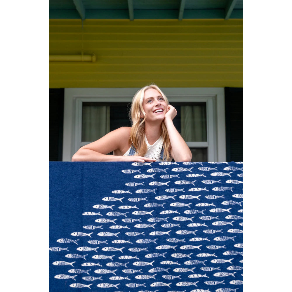 Woman sitting on a balcony with a blue fish-patterned blanket