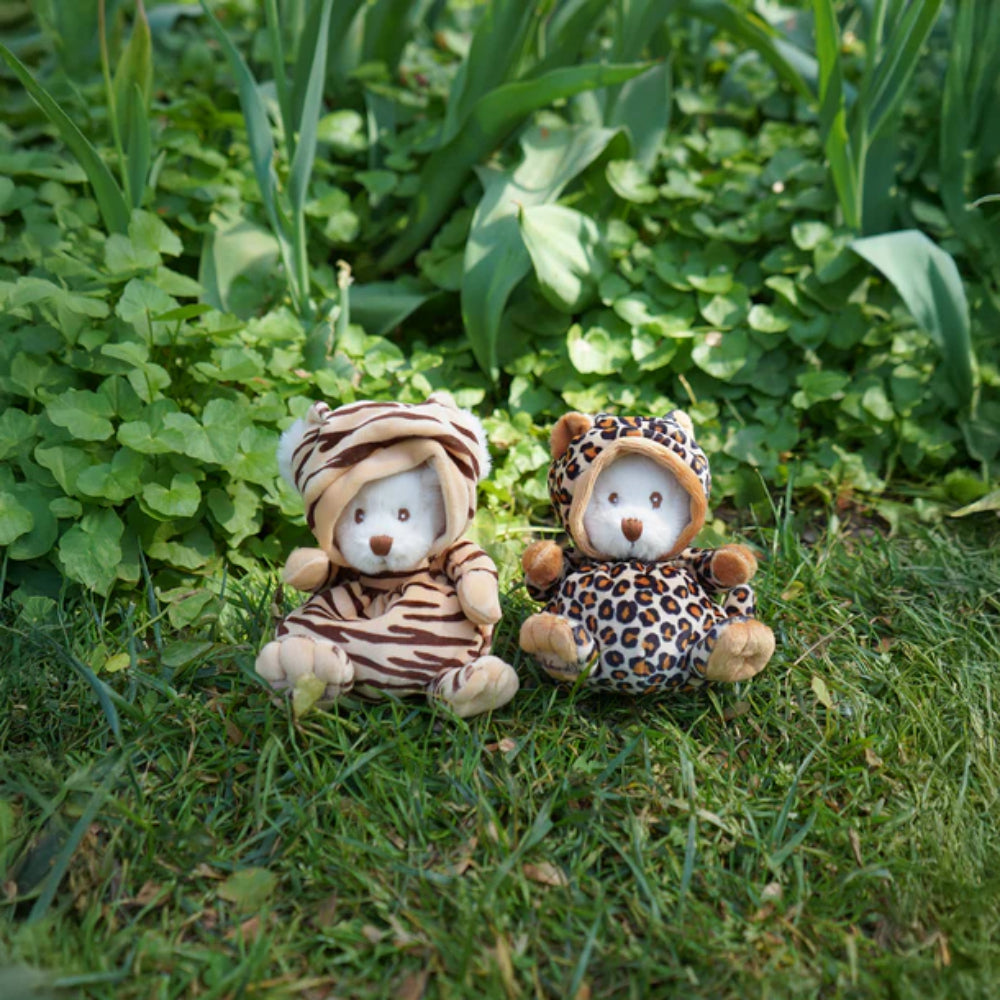 Two white teddy bears in animal print outfits sitting on grass.