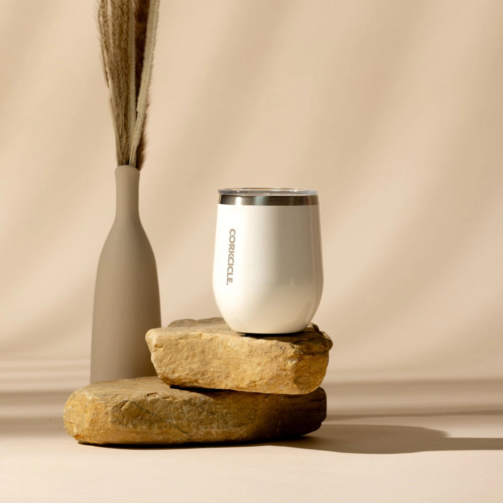 White insulated tumbler on tan rocks with a beige background.