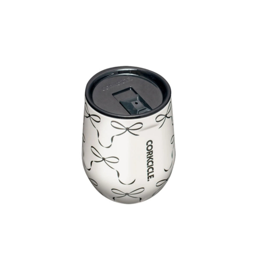 White tumbler with black bow pattern and with black lid with a Corkcicle logo in black on a white background.